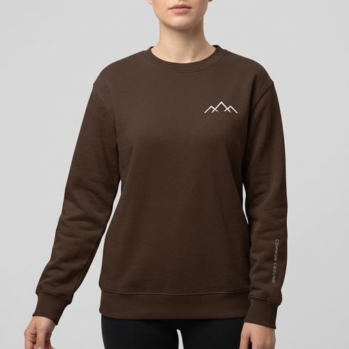 Women’s dark-brown crewneck mockup with a small mountain logo on the right chest and subtle Common Ground lettering down the left sleeve